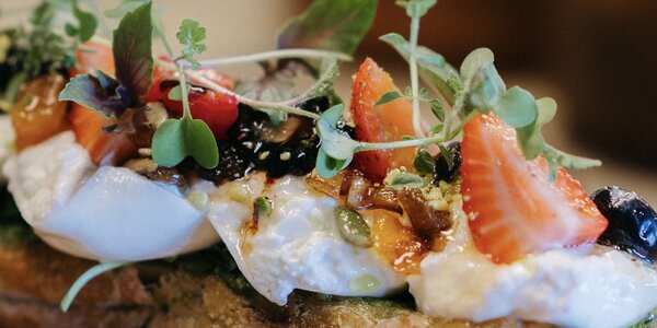 Burrata en pan cristal con frutas deshidratadas tostadas con mantequilla y miel, pesto, rúcula.