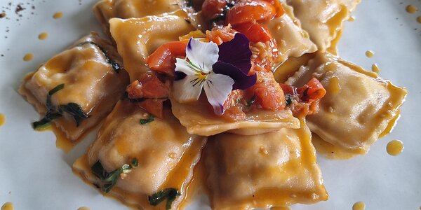 Ravioli rossi al pomodoro con mazzancolle e patate, pomodorini freschi e aglio nero